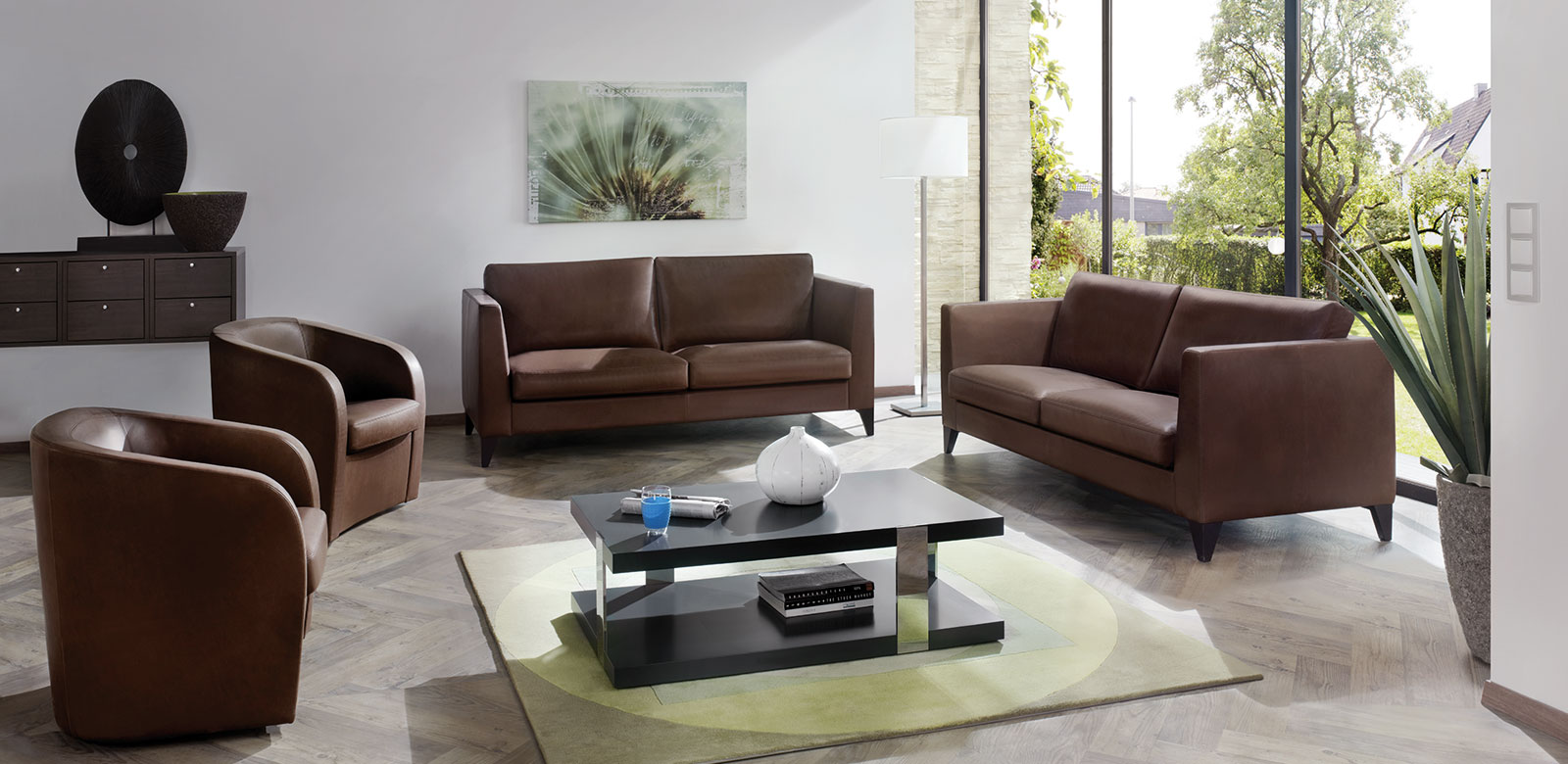 Zwei CL850 Sofas aus braunem Leder mit passenden Sesseln und eckigem Couchtisch im Wohnzimmer mit Gartenzugang