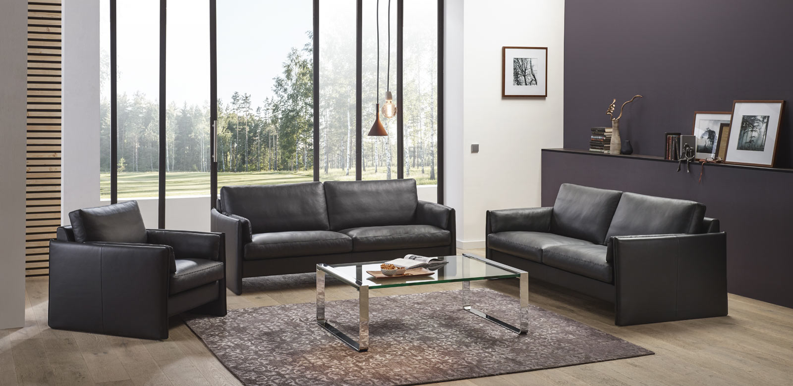 Black CL810 leather couches with matching armchair and glass table in modern living room