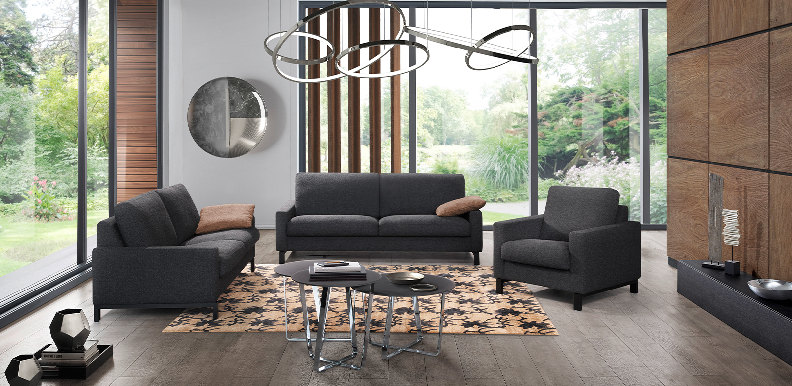 Moderne woonkamer met houten elementen en twee CL500 banken en fauteuils in grijs-zwarte stof.