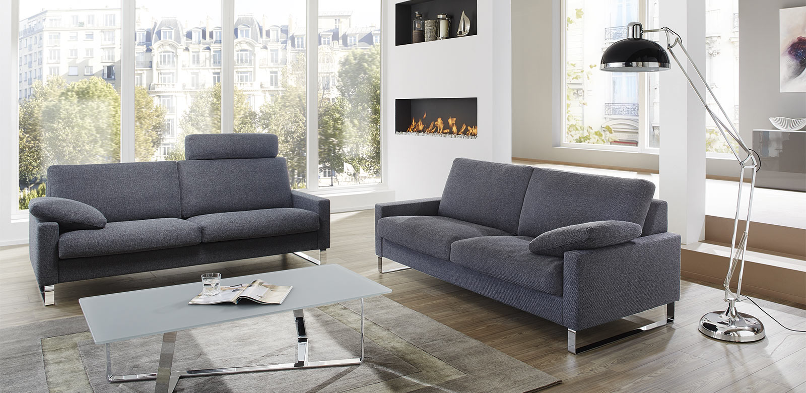 CL500 Sofas mit Kissen und Kopfstützen aus grau-blauem Stoff in modernem Apartment mit Stadtsicht und Kamin.