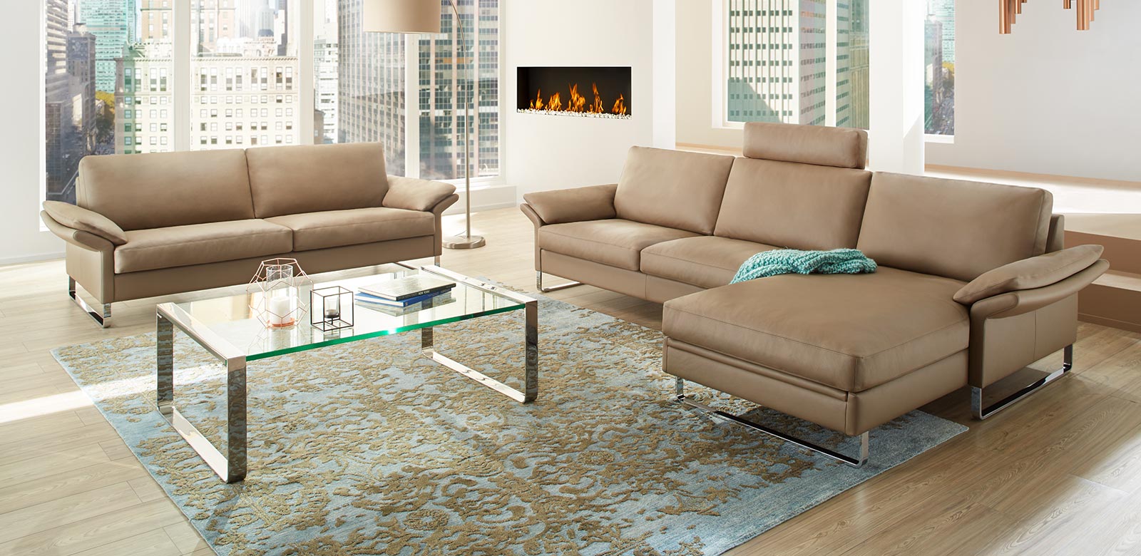 CL960 bank en fauteuil combinatie in crème leer, sierlijk tapijt en open haard in de woonkamer van een hoogbouw appartement