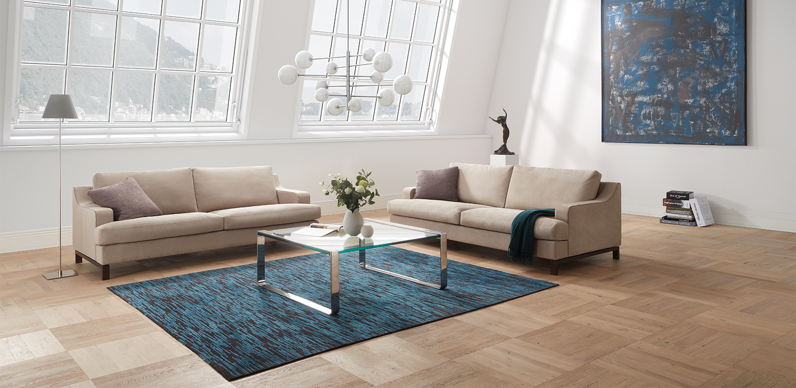 CL770 Sofas aus beigem Leder mit Glastisch auf blauem Teppich in weitläufigem Wohnzimmers eines Industrie-Lofts
