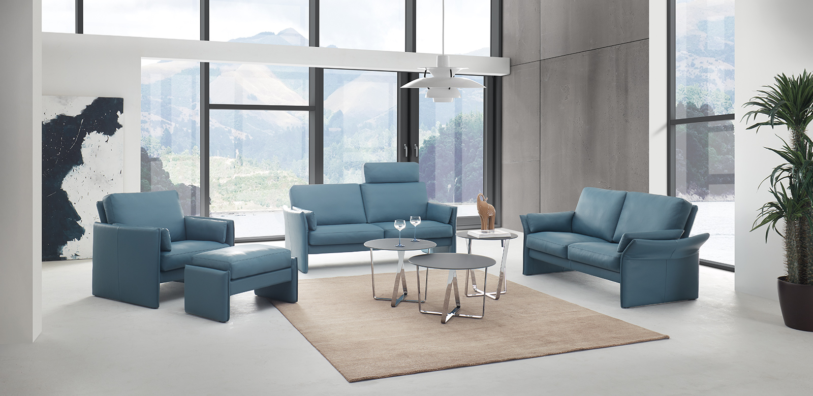 Sevilla seating group consisting of two sofas with headboard, folding armrests and armchair with stool in grey-blue leather in modern, cubist villa.